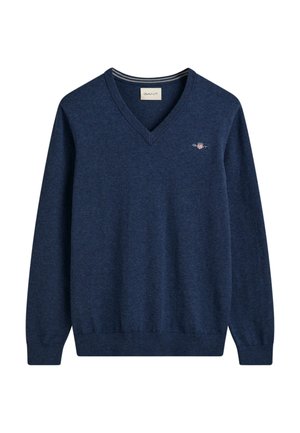 Suéter de pico azul marino hecho de un material de punto suave, con un pequeño logo bordado en el pecho y puños y dobladillo acanalados.