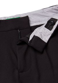 Černé kalhoty s hladkým povrchem, s šedým pruhovaným pasem, knoflíkovým detailem a boční kapsou na zip.