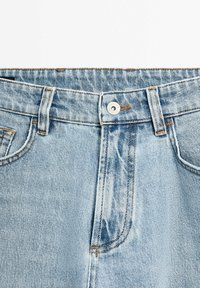 Light blue denim jeans with a button closure, stitched waistband, and front pockets. Features a faded pattern with contrast stitching.