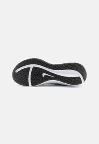 Semelle de basket en caoutchouc noire avec un motif hexagonal texturé, présentant un accent blanc et une ligne blanche courbée le long du bord.
