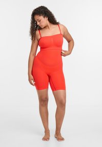 Červený bodysuit s nastavitelnými ramínky, bezešvým designem, přiléhavým střihem na bocích, hladkým texturem a šortkami ke kolenům.