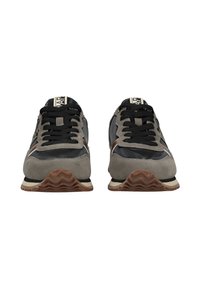 Para szarych i czarnych sneakersów z czarnymi sznurówkami i brązowymi falistymi podeszwami, pokazana z przodu na białym tle.