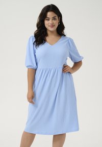 Lichtblauwe jurk van gestructureerde stof met een V-hals, korte pofmouwen en een geplooide taille, vallend onder de knie.