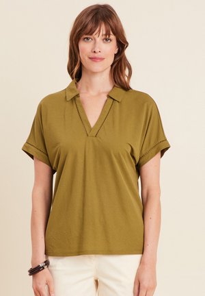 Haut vert olive à manches courtes avec un décolleté en V, des poignets repliés et des détails de couture contrastants. Tissu doux avec une coupe décontractée.