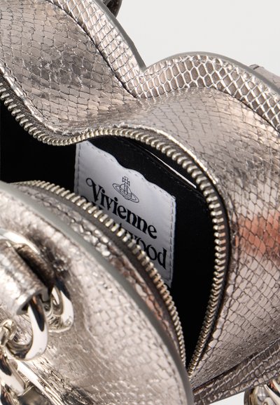 Μεταλλική ασημένια τσάντα με υφή, με ανοιχτό φερμουάρ που αποκαλύπτει την λευκή ετικέτα Vivienne Westwood στο εσωτερικό.