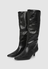 Stivali neri al ginocchio in pelle lucida, con punta affusolata e tacco kitten sottile. Texture liscia con dettagli minimi.