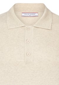 Beige poloshirt med tekstureret krave og tre-knaps slids. Fremstillet af blødt materiale, med et mærke, der viser "FELIX HARDY" branding.