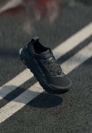 Zwarte sportschoen met een textuur bovenkant, vetersluiting, gevoerde zool en Vibram-buitenzool, voorzien van perforaties voor ademend vermogen.