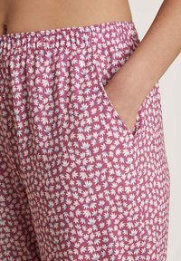 Paarse elastische broek met een bloemmotief in wit en lichtblauw; heeft zijzakken en een zachte, lichte stof.