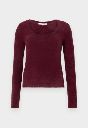 Dolga rokavica, bordo puhasta pulover s krojnim izrezom, prikazana na beli podlagi.