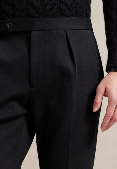 Μαύρο παντελόνι με καλοραμμένη γραμμή, κατασκευασμένο από λείο ύφασμα, με πιέτες και κλείσιμο με κουμπί στη μέση. Διακριτή υφή και εφαρμοστή εμφάνιση.
