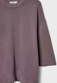 Fioletowa bluza z luźnym krojem, okrągłym dekoltem i opadającymi ramionami. Wykonana z miękkiego materiału z prążkowanym wykończeniem u dołu i na mankietach.