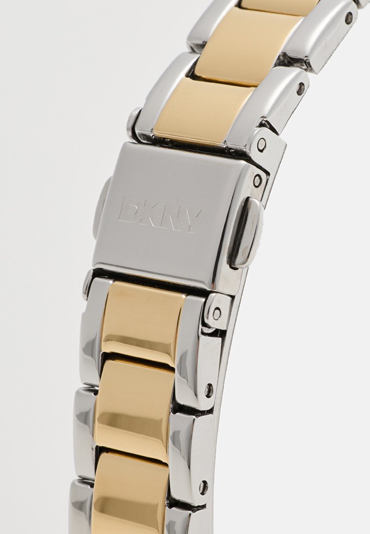 Bracciale in acciaio inox per orologio con maglie in metallo color oro, con superficie lucidata e il logo DKNY inciso sulla chiusura.