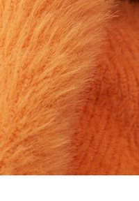 Oranje textiel met een zachte, pluizige sectie naast een fijn gebreid deel. Beide secties stralen warmte en levendige kleuren uit.