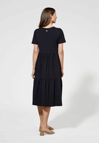 Czarna sukienka warstwowa wykonana z miękkiej tkaniny, z krótkimi rękawami i okrągłym dekoltem, z małym logo z tyłu.