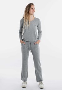 Grijze lange mouw top en bijpassende sweatpants, beide gemaakt van zachte stof. De broek heeft een trekkoord en voorzakken. Witte sneakers inbegrepen.