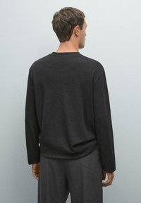 Donkergrijze long-sleeve top met een ronde hals, met een relaxed fit en een gladde textuur. De achterkant heeft minimaal ontwerpdetails.