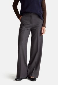 Szerokie spodnie wykonane z szarego materiału, z dopasowanym krojem, plisami z przodu i średnim stanem. Czółenka w kolorze czarnym dopełniają całość.