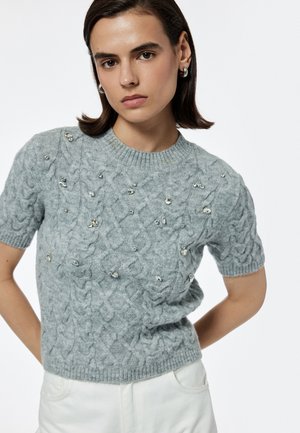 Maglione grigio a maniche corte lavorato a maglia con motivo a trecce, abbellito da gemme sparse e con scollo e orlo a coste.