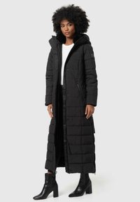 Manteau long rembourré noir avec capuche, présentant un design matelassé, des fermetures éclair et à pression, ainsi qu'un logo sur le devant.