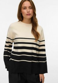 Maglione a righe crema e nero con scollatura rotonda, vestibilità ampia e texture a coste. Presenta ampie righe orizzontali e maniche lunghe.