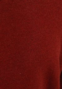 Strickpullover in einem tiefen Rotton, mit einer weichen Textur und einem glatten Finish. Es sind keine sichtbaren Muster oder Hardwaredetails vorhanden.