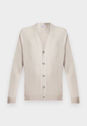 Bēša garām piedurknēm ar pogām aiztaisāma kardigana ar V veida izgriezumu, ribām pie manžetēm un apakšmalas, nolikta uz plakana virsmas uz vienkrāsaina fona.