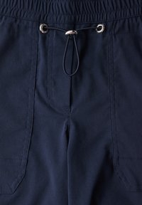 Shorts bleu marine en tissu léger, dotés d'une taille élastique, d'une fermeture à cordon, et de deux poches latérales avec bords cousus.