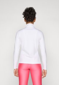 Long-sleeve, white athletic top with a high collar, smooth texture, and fitted design, paired with pink leggings.