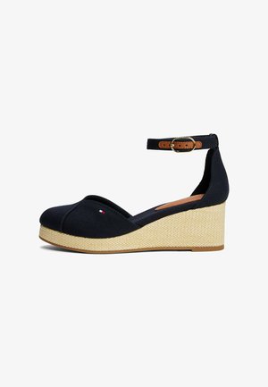 Navy wedge sandals with a canvas upper, adjustable ankle strap, and woven texture on the platform, featuring a small logo detail.