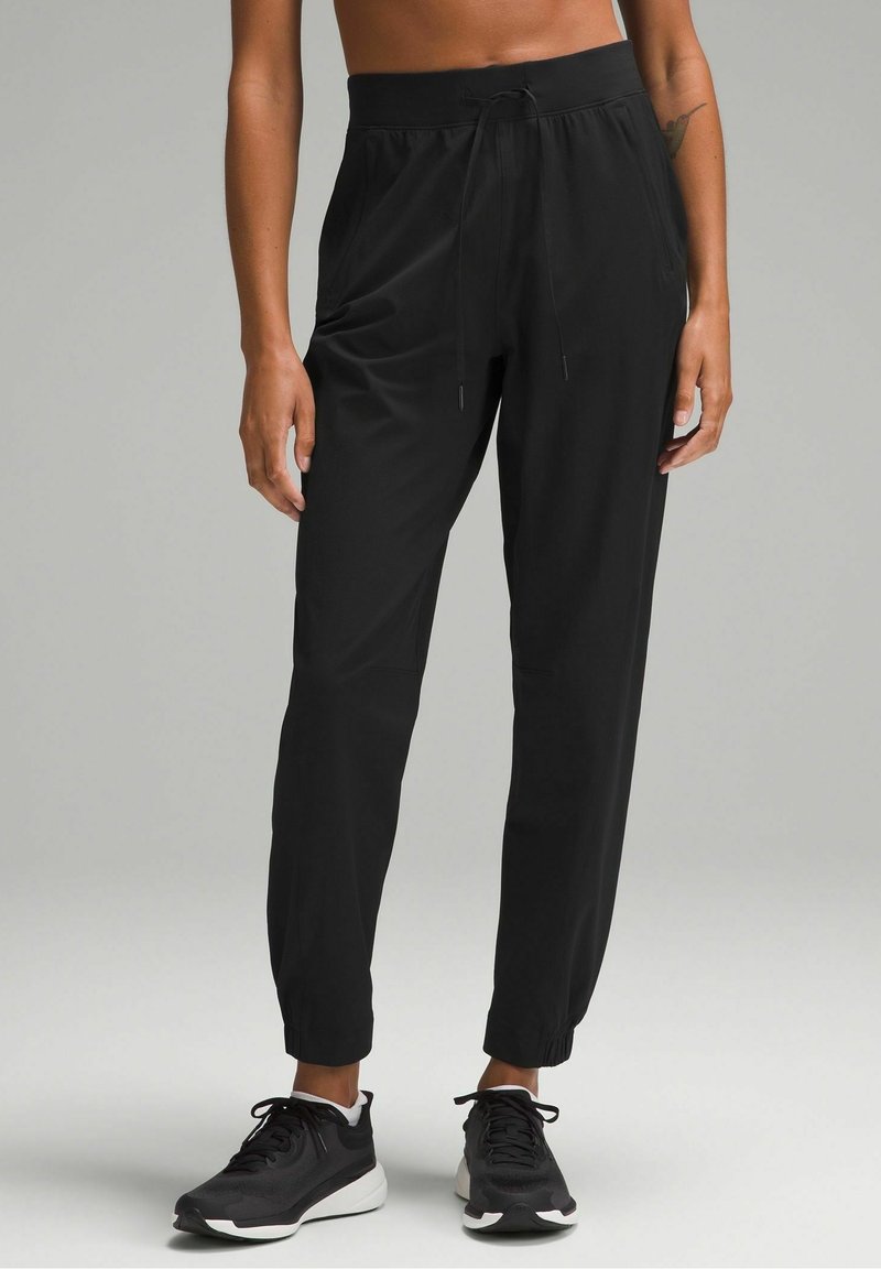 Black athletic pants with a drawstring waist, tapered fit, and elastic cuffs. Made of lightweight material, suitable for active wear.