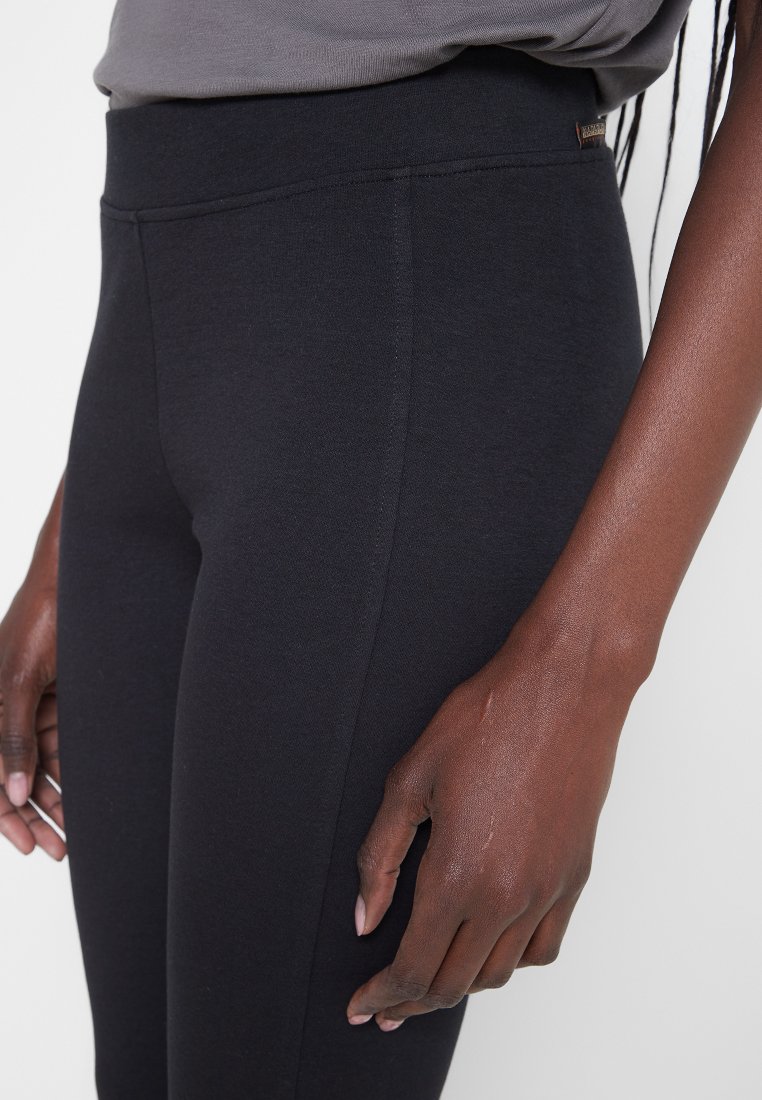Leggings negros de cintura alta hechos de un tejido elástico, con una textura suave y un detalle de costura mínimo para un aspecto sin costuras.
