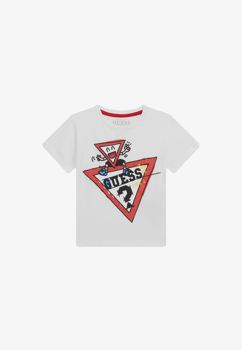 Valge T-särk, kus on mänguline disain naeratava kolmnurga tegelasega, punane kolmnurkne logo ja julged mustad tähed "GUESS."