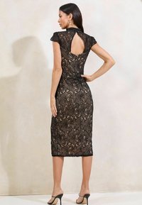 Black lace dress with a fitted silhouette, cap sleeves, and a keyhole back detail. The dress features floral patterns and falls to mid-calf length.
