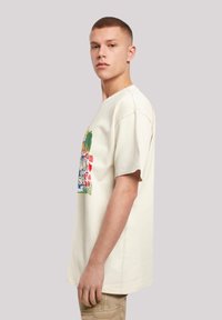 Light cream oversized t-shirt made of cotton, featuring a colorful tropical graphic design on the front. Short sleeves, relaxed fit.