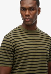 Short-sleeve t-shirt in olive green with horizontal black stripes, featuring a crew neck and soft fabric texture.