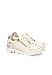Baskets crème et beige avec fermeture éclair, motif texturé et accents dorés. Semelle blanche épaisse avec un léger talon et finition lisse.