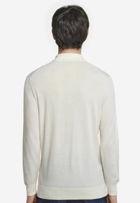 Ljusbeige långärmad polotröja i mjukt, texturerat tyg, med ribbad krage och manschetter samt rak nederkant.