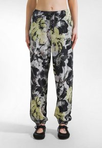 Musta-valko-limetinvihreällä kukkakuviolla koristellut collegehousut, joissa on joustava vyötärönauha ja käännetyt lahkeet. Valmistettu kevyestä kankaasta.