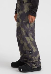 Camo-gepatroneerde sneeuwbroeken van duurzaam materiaal, met groene en zwarte kleuren, een ruime pasvorm en versterkte naden.