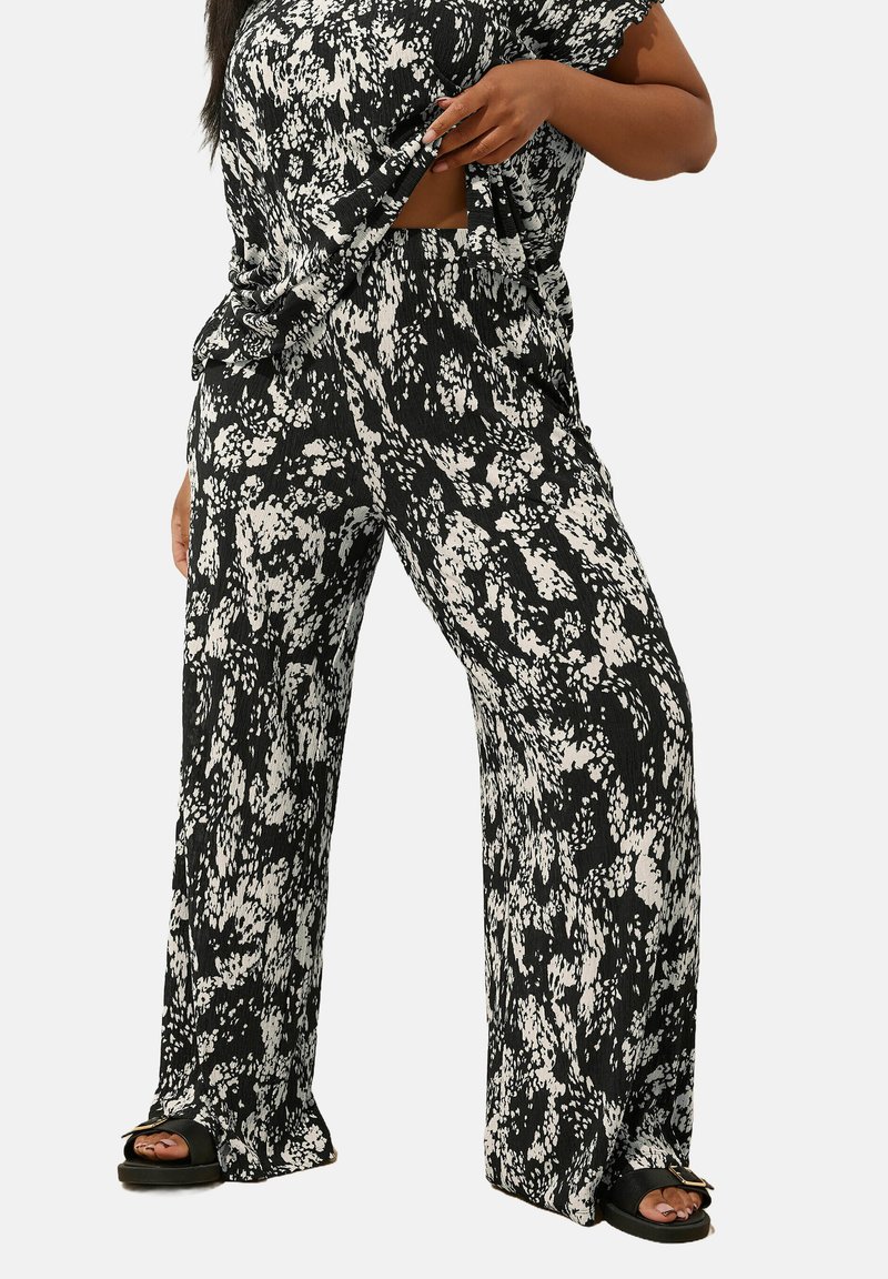 Svarta och vita mönstrade byxor med vida ben, tillverkade av texturerat tyg, med elastisk midja och avslappnad passform. Tillsammans med svarta sandaler.