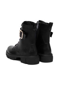 Čierne kožené členkové topánky s masívnou podrážkou, zlatou prackou a zipsom na zadnej strane. Majú okrúhlu špičku a pevnú šnurovaciu prednú časť.