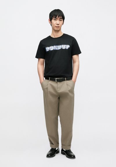 Μαύρο μπλουζάκι με το γραφικό «DON DUP» σε μπλε απόχρωση, σε συνδυασμό με μπεζ πλισέ παντελόνια και μαύρα παπούτσια, με ομαλή υφή και άνετη εφαρμογή.