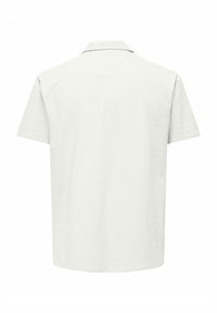 Kortærmet polo shirt i lys grå, struktureret stof med et subtilt mønster, der har klassisk krave og ingen synlig hardware.