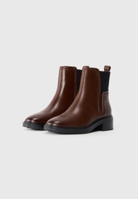Brown leather ankle boots with a smooth finish, elastic side panels, and a low block heel. Features a pull tab at the back.