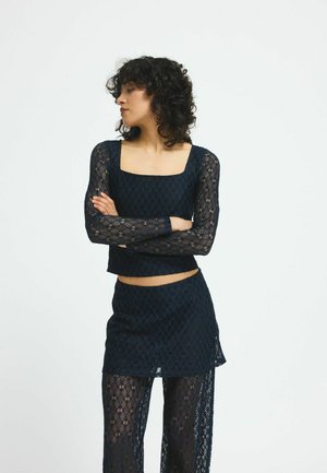 Navy blue lace two-piece set featuring a long-sleeve cropped top with a square neckline and a matching mini skirt with sheer trousers.