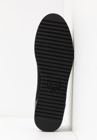 Semelle de chaussure noire avec des rainures horizontales, dotée d'une finition texturée et des marquages "ANNA FIELD" et "37" pour la taille. Détail de bord lisse.