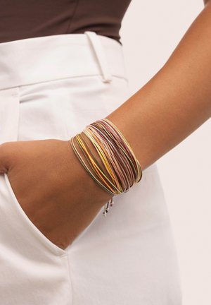 Pulseras de bangle de colores múltiples hechas de finas hebras de metal, con una mezcla de tonalidades doradas, rosas y plateadas, superpuestas en una muñeca.