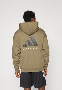 Olive green hoodie with a large black logo and white text “BASKETBALL” on the back; features a kangaroo pocket and drawstring hood.