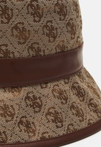 Chapeau de seau marron avec une texture tissée, présentant un extérieur à motifs et une bande en cuir marron lisse autour de la base.